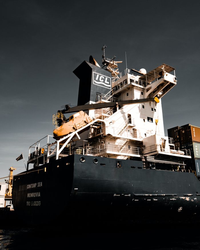 Large cargo vessel docked at Istanbul harbor under dramatic skies, showcasing global trade.
