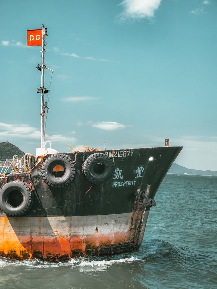 A cargo ship labeled 'Prosperity' sails peacefully on the ocean under a clear blue sky.